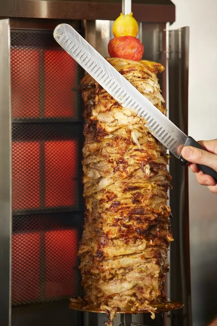 Chicken shawarma being carved from the spit in the Palmyra kitchen